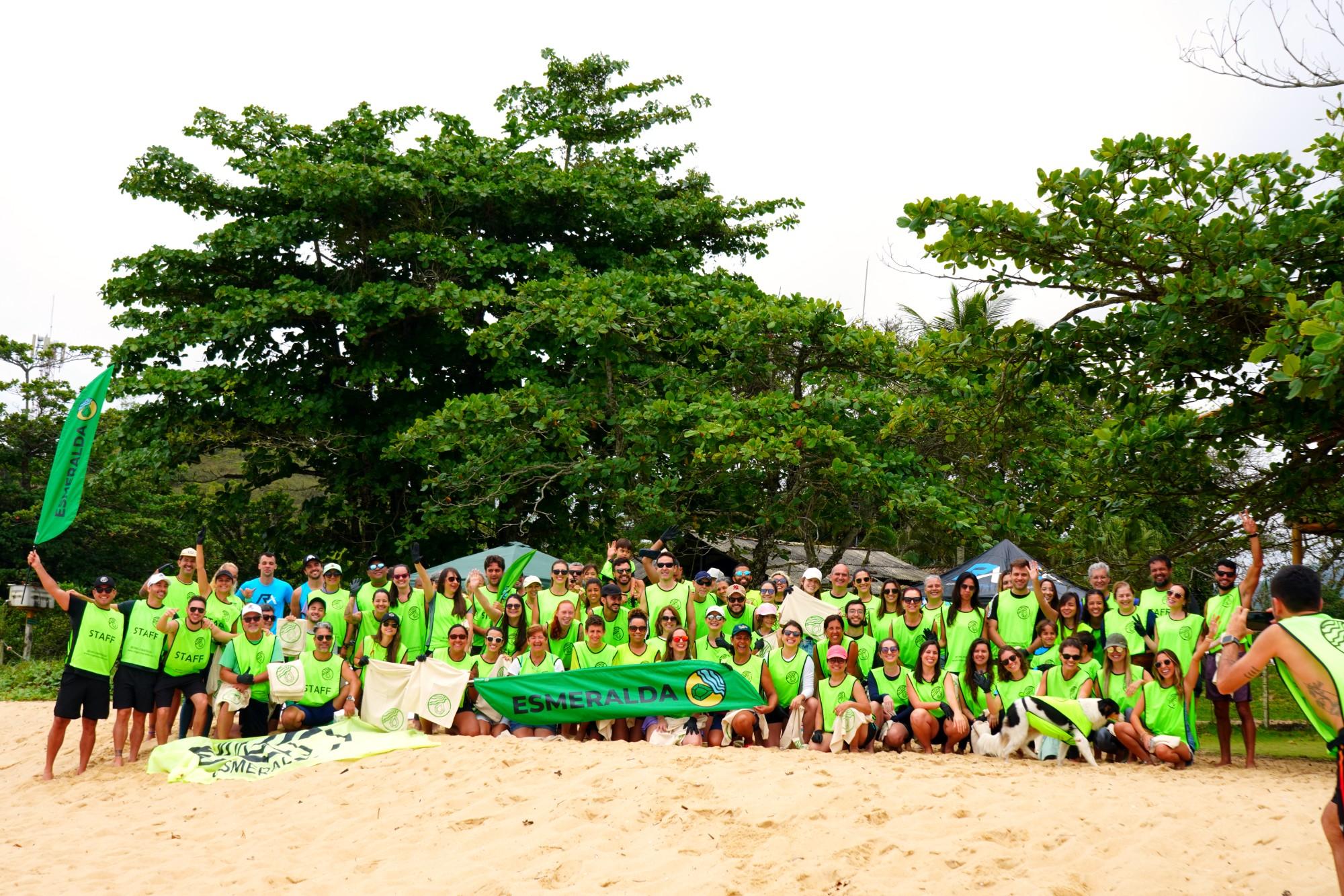 Voluntários da Esmeralda reunidos na praia com a bandeira